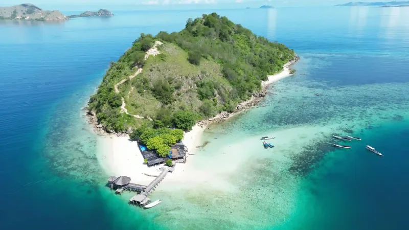 Aerial view of Kelor Island with day boats moored on the reef shelf beside it