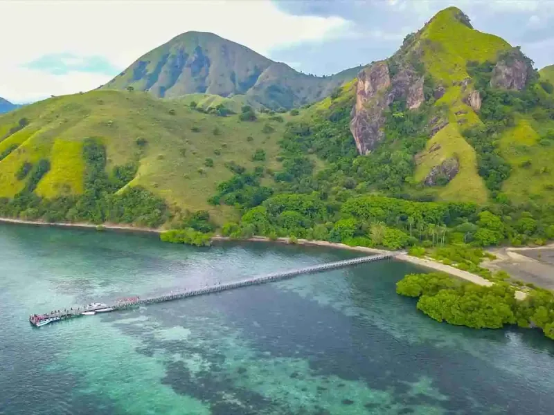 Aerial view of Manjarite: a long jetty running out over shallow water below steep green hills