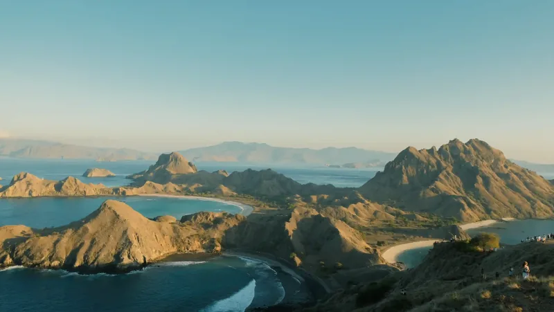 The view from the Padar Island ridge, curved bays on either side and walkers on the path