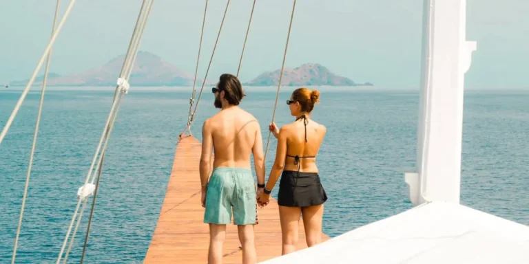 Couple walking along a phinisi bowsprit in Komodo