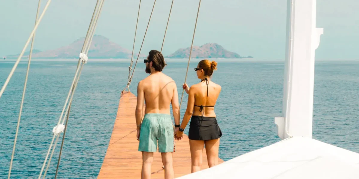 Couple walking along a phinisi bowsprit in Komodo