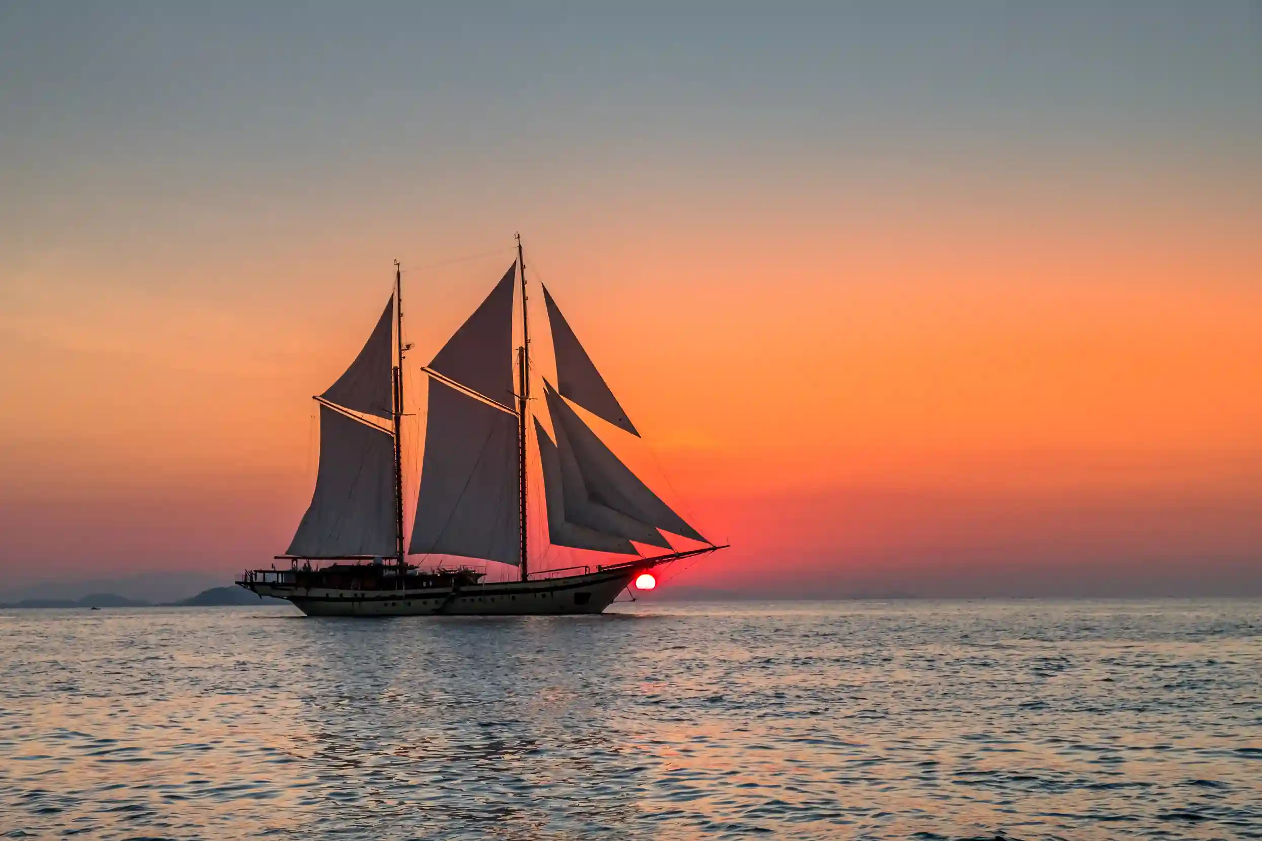 Traditional phinisi sailing at sunset off Komodo
